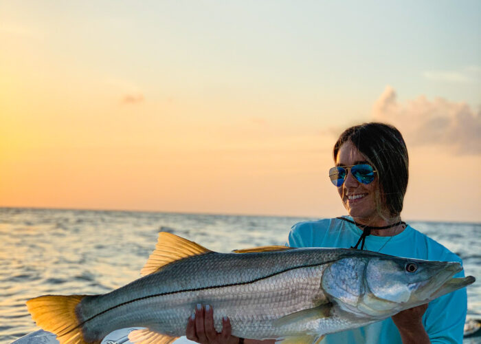 A woman showcasing a massive striped bass catch during a fishing charter.