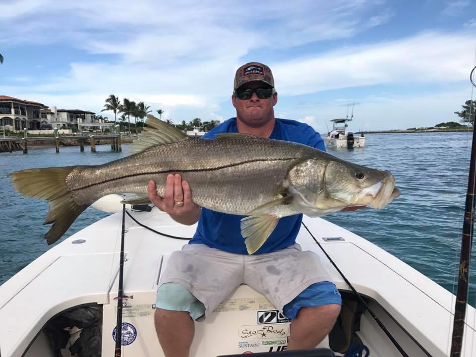 A man proudly displaying a snook during a fishing trip.